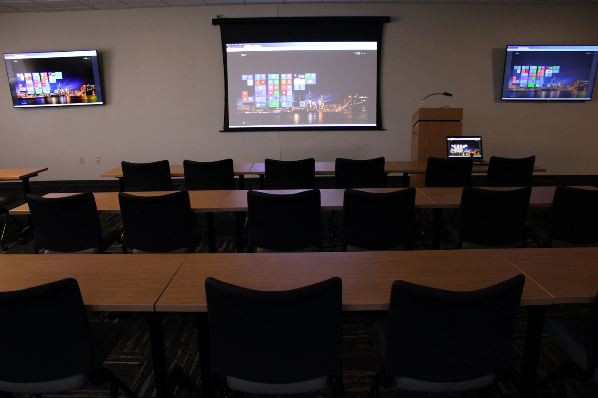 Sharp Packaging’s training room with a projection screen and supporting displays.