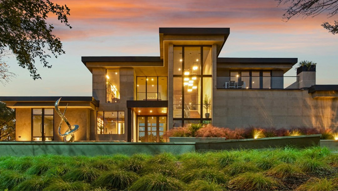 Architectural luxury residence at dusk with illuminated interiors